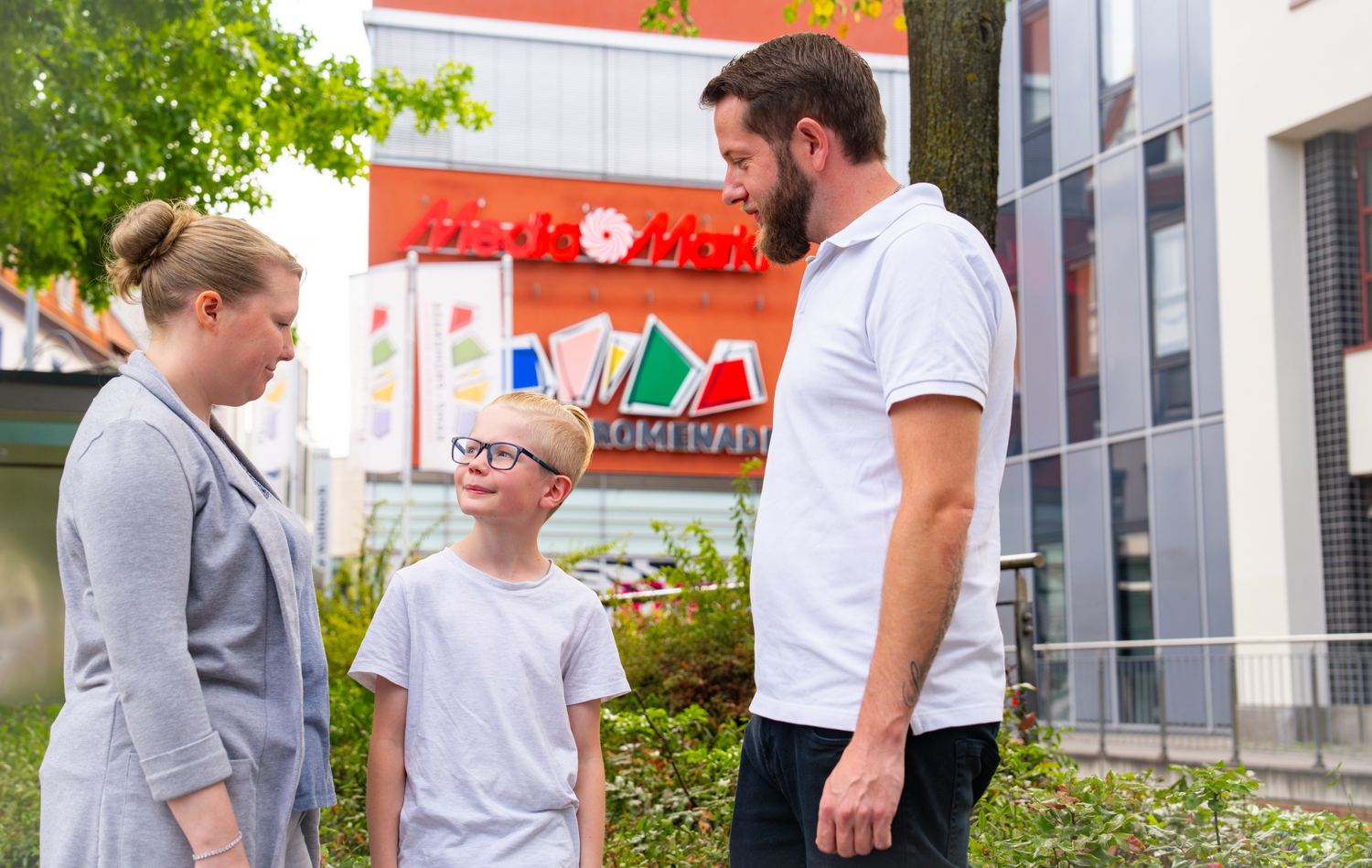 Vater, Mutter und Sohn stehen am Kamp vor dem Eingang der Promenade und unterhalten sich.